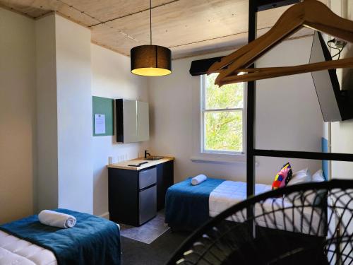 a bedroom with two beds and a desk and a ladder at Urban Lounge Sleepery Carterton in Carterton