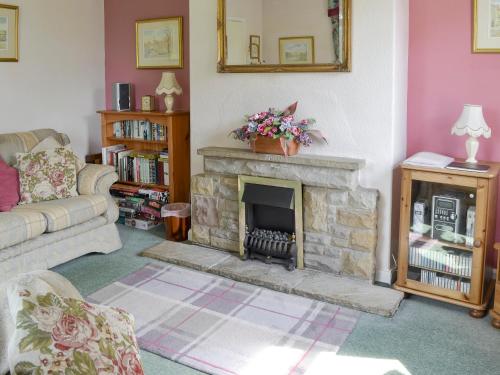 a living room with a fireplace and a couch at Peasholm in Thornton Dale