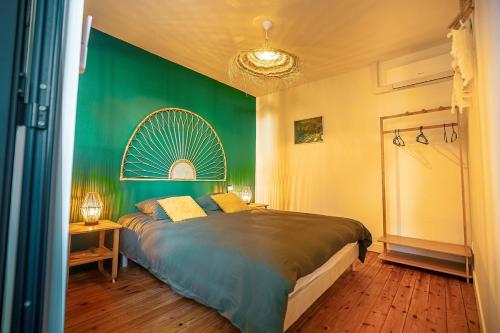 a bedroom with a large bed with a green wall at L Escale Balinaise et Spa #7 in Agen