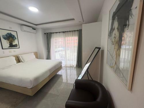 a bedroom with a bed and a chair and a window at Les Sublimes Residences Tweens in Abidjan