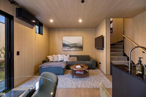 a living room with a couch and a staircase at Wakatipu Villa, Queenstown in Queenstown