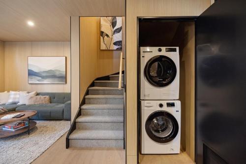 a living room with a washer and dryer next to a staircase at Wakatipu Villa, Queenstown in Queenstown