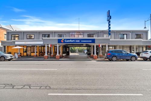 a building with cars parked in front of a street at Comfort Inn Commodore Albury in Albury