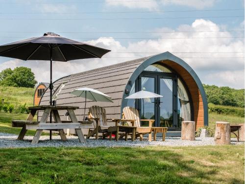 a cabin with a table and chairs and an umbrella at Hayfield Haven-Uk40691 in Crowhurst