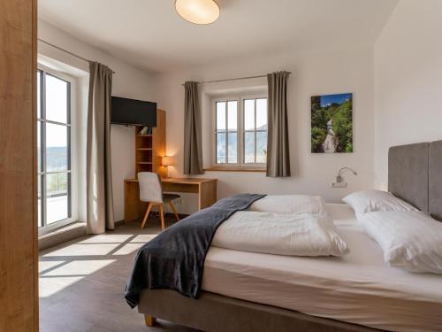 a bedroom with a bed and a desk and windows at Lärchenhof Top 101 in Mauterndorf