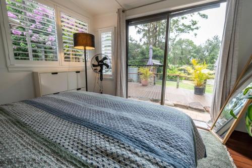 a bedroom with a bed and a large window at The Lotus Cottage Maleny in Witta