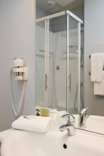 a bathroom with a sink and a mirror at The Originals City, Hôtel Le Causséa, Castres in Castres