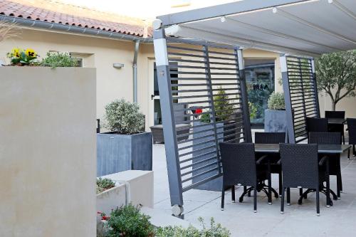 a patio with a table and chairs under a pergola at The Originals City, Hôtel Le Causséa, Castres in Castres