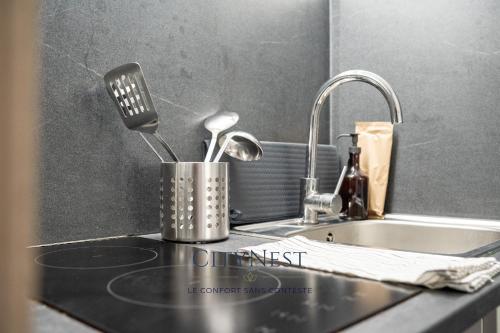 a kitchen counter with a sink and a kitchen utensils at Confort et élégance proche centre in Schiltigheim