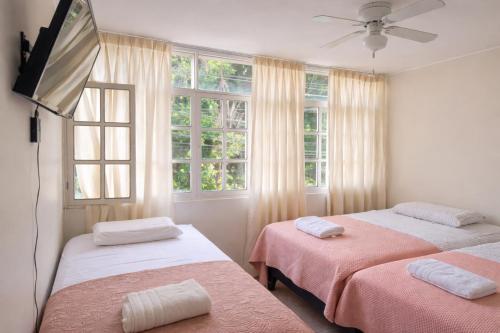 two beds in a room with two windows at Huacachina Boutique Hotel in Ica