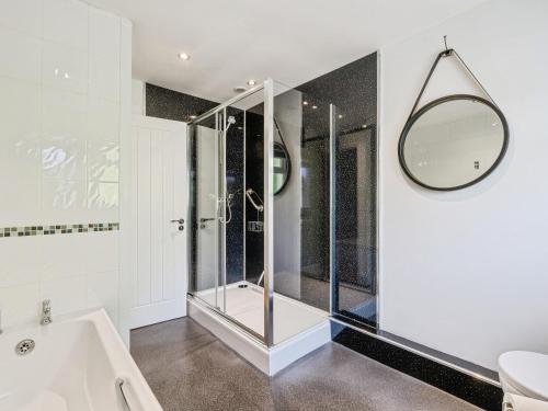 a bathroom with a shower and a tub and a mirror at Mylnebeck Lodge in Windermere