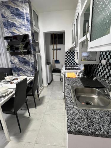 a kitchen with a sink and a table with chairs at Residencial christall ap 2-A in Santiago de los Caballeros