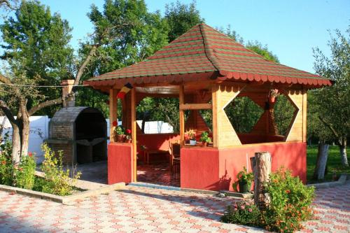 a wooden gazebo with a fireplace in a yard at Pensiunea Soreanca in Costeşti