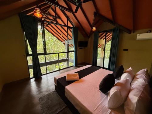 a bedroom with a large bed in a room with windows at Forest Shade Eco Resort Deraniyagala in Deraniyagala