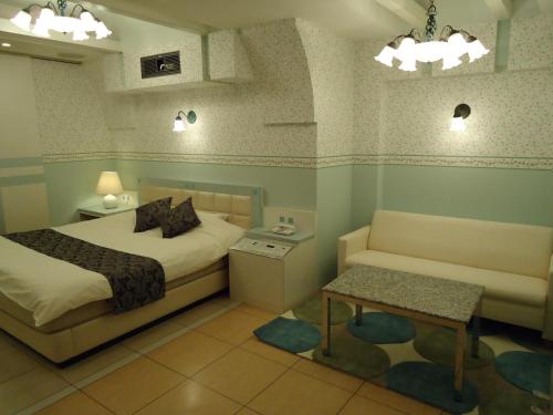 a bedroom with a bed and a couch and a table at ホテル アイアンプレミアム 六甲店 Adult only男塾ホテルグループ in Kobe