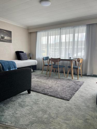 a living room with a table and chairs and a bed at ASURE Surrey Court Motel Invercargill in Invercargill