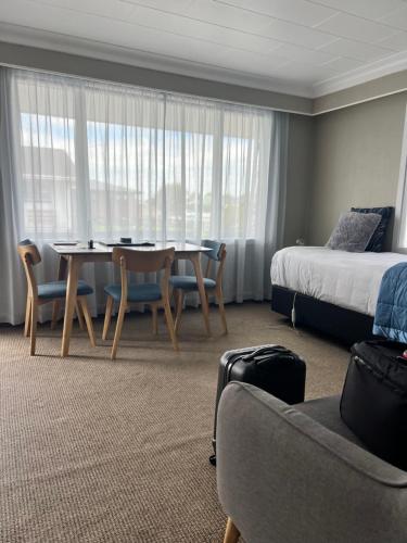 a hotel room with a table and chairs and a bed at ASURE Surrey Court Motel Invercargill in Invercargill