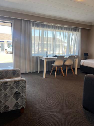 a hotel room with a bed and a table and chairs at ASURE Surrey Court Motel Invercargill in Invercargill