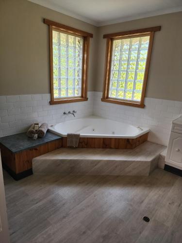 a large bath tub in a bathroom with two windows at Kentish Hills Retreat in Sheffield