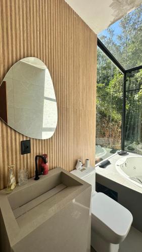 a bathroom with a toilet and a sink and a mirror at Cabana de Vidro - Canelinha in Canelinha