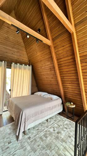 a bed in a room with a wooden ceiling at Cabana de Vidro - Canelinha in Canelinha