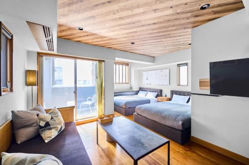 a living room with two beds and a flat screen tv at Hotel Vintage Tokyo Tsukiji in Tokyo