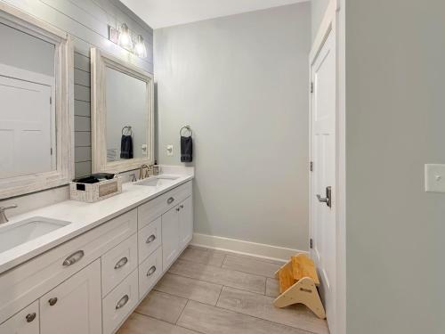 a white bathroom with two sinks and a mirror at Live Oak Cottage OKI Beach Retreat in Oak Island