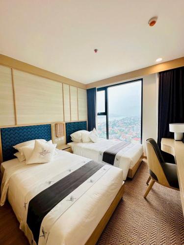 two beds in a hotel room with a large window at Lynntime in La Phu