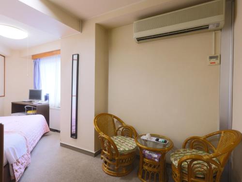 a bedroom with a bed and chairs and a desk at Hotel Sunplaza Tsugaike in Otari