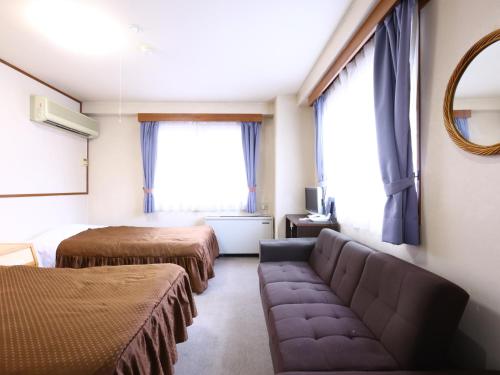 a room with two beds and a couch and a mirror at Hotel Sunplaza Tsugaike in Otari