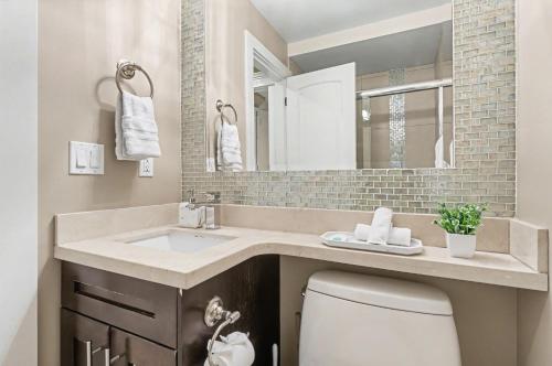 a bathroom with a sink and a toilet and a mirror at Secluded Bachelor Suite in Vancouver