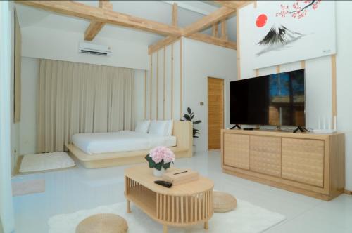 a living room with a television and a bed at Japanese house PhuSaimorkVilla in Ban Kai Noi