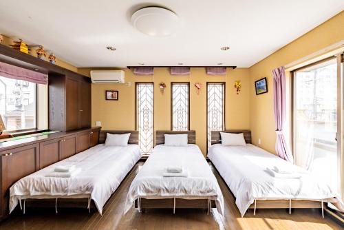 two beds in a room with windows at Chouetteの宿 橿原店 橿原神宫前駅から歩いて4分 in Kashihara