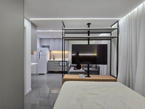 a room with a bed and a kitchen with a television at Studio - Quaddra Butantã NOVÍSSIMO MODERNO - Academia - Piscina - 5min Metrô e USP in São Paulo