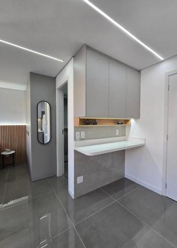 a kitchen with white cabinets and a mirror on the wall at Studio - Quaddra Butantã NOVÍSSIMO MODERNO - Academia - Piscina - 5min Metrô e USP in São Paulo