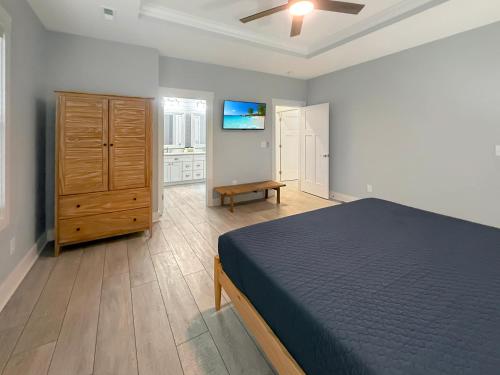 a bedroom with a bed and a wooden dresser at Live Oak Cottage OKI Beach Retreat in Oak Island