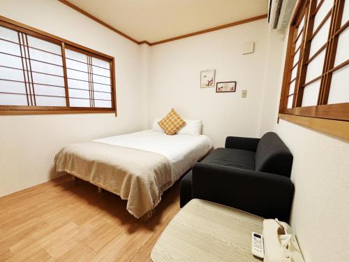a bedroom with a bed and a couch and a window at 時旅ー大正 in Osaka