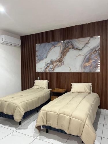 two beds in a room with a painting on the wall at Valle Stay in Cedro