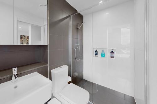 a white bathroom with a toilet and a sink at Elegant Urban Hideaway - Private Luxury Residential Apartment, walk to South Bank & Free Carpark in Brisbane