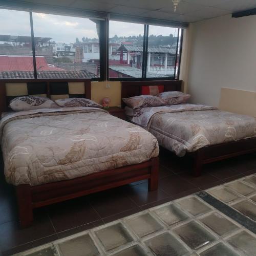 a bedroom with two beds and a large window at Departamento MEDIO DIA in Quito