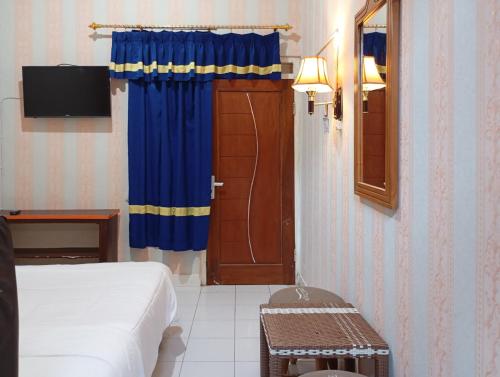 a bedroom with a bed and a door with a television at Roemah Djogja Inn Seturan Raya RedPartner in Seturan