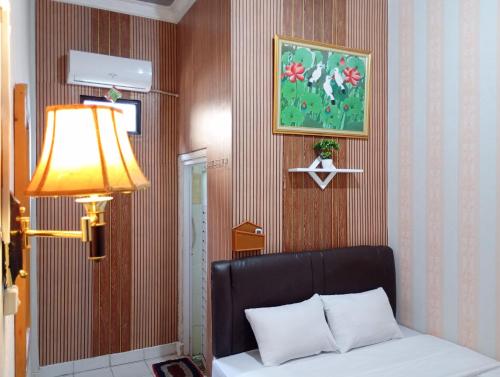 a bedroom with a bed and a lamp and a picture at Roemah Djogja Inn Seturan Raya RedPartner in Seturan