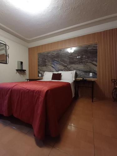 a hotel room with a large bed with red sheets at Hotel La Paz in Guadalajara