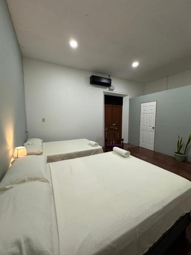 two beds in a room with white walls at Hostal El Amate #2 in Suchitoto