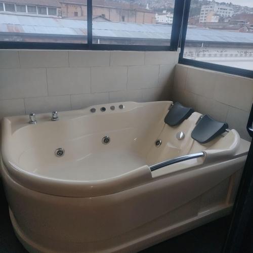 a white bath tub in a bathroom with a window at Departamento MEDIO DIA in Quito