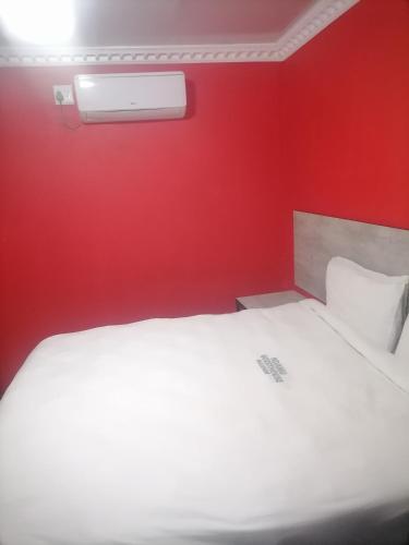 a bedroom with a white bed and a red wall at Ndamu guesthouse in Vosburg
