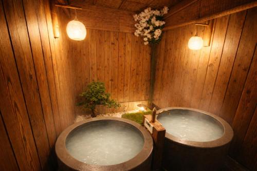 a bathroom with two tubs in a wooden wall at NEW OPEN 庭音日和 一棟貸し 八幡堀徒歩9分 壺湯2つ 近江牛名店至近 子連れ歓迎 水回り2箇所 p2台 in Omihachiman