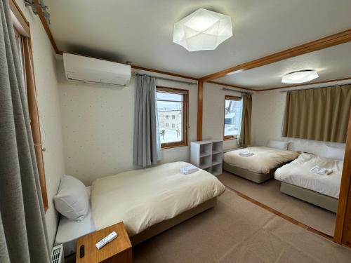 a small room with two beds and a window at Chalet Yutaka in Furano