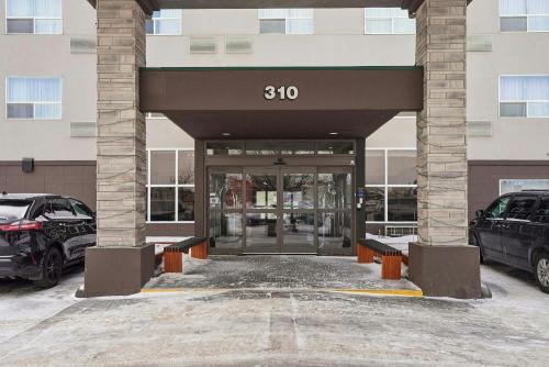 a building with a parking lot with cars parked in front at Sandman Hotel Saskatoon in Saskatoon