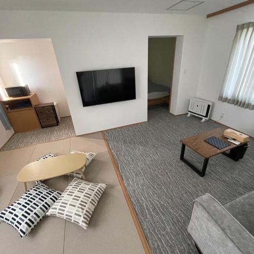 a living room with a flat screen tv on a wall at お宿 垢田の杜　桂月 in Hatabu